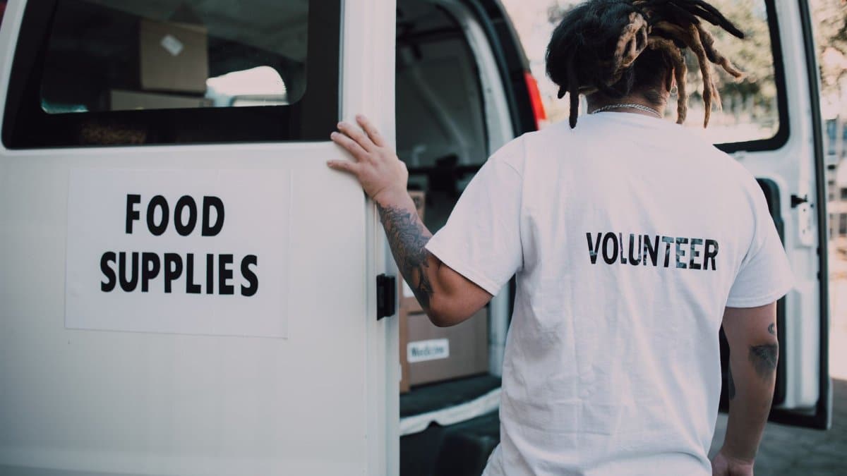 A volunteer loads food supplies into a van, showcasing charity and community support.