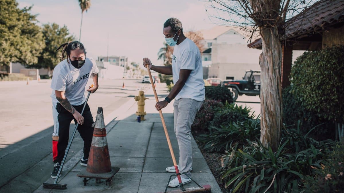 Two volunteers engaged in a street cleaning effort, promoting social good and community service.