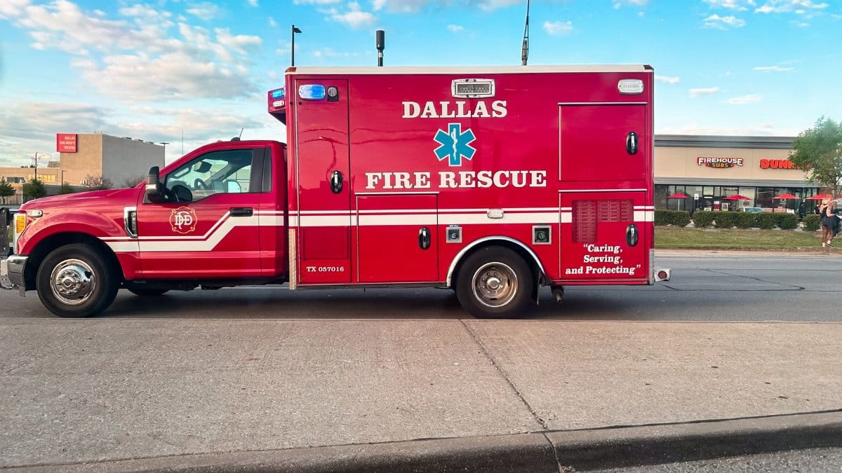 Red Dallas Fire Rescue ambulance parked on a sunny street in Texas.