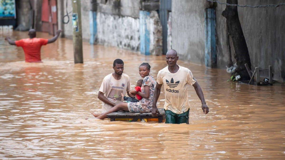 People navigating a flooded street, showcasing resilience amidst natural disaster in Africa.