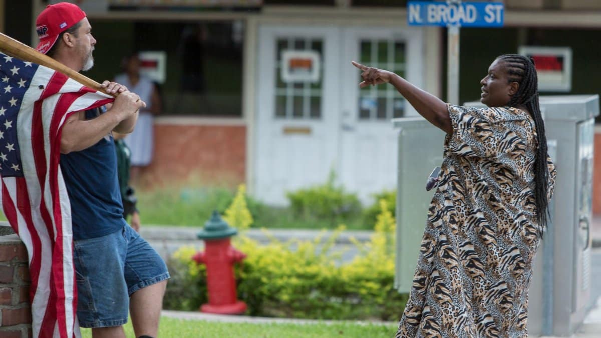 A man with an American flag converses with a woman on North Broad Street in Brooksville, Florida.