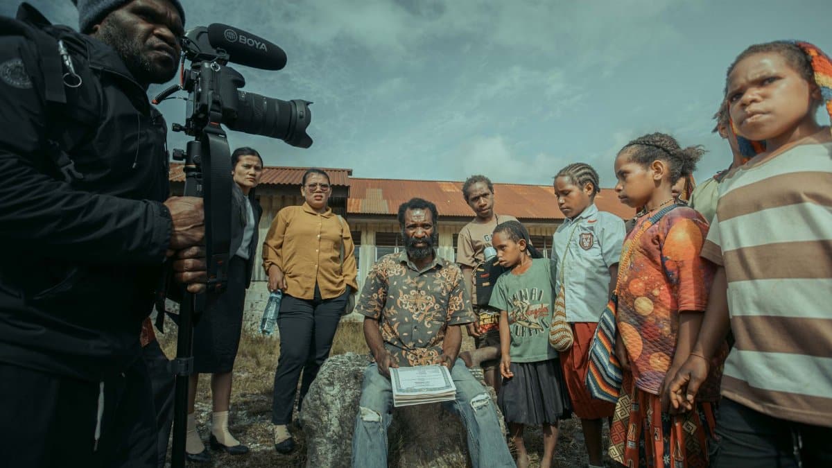 A filmmaker capturing a diverse group of people outdoors, emphasizing community and storytelling.
