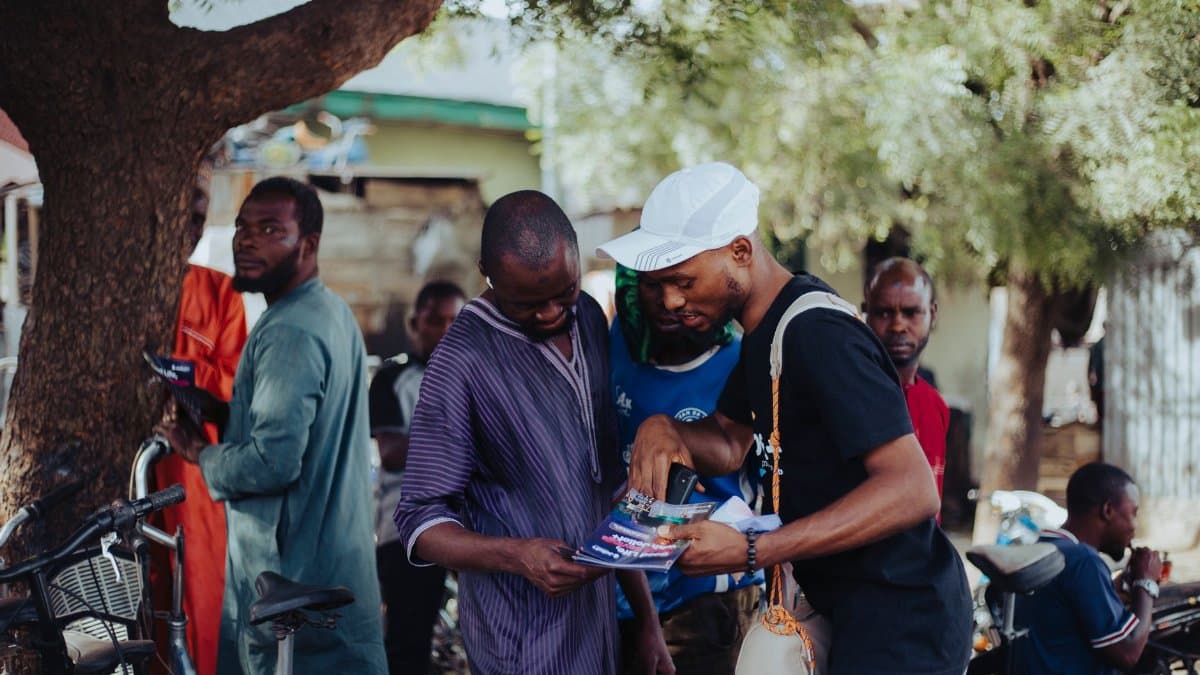 Men engaging in conversation under a tree in a vibrant urban community.
