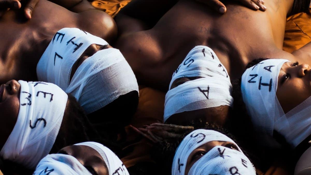Artistic portrayal of individuals with bandaged faces lying together, highlighting unity and anonymity.