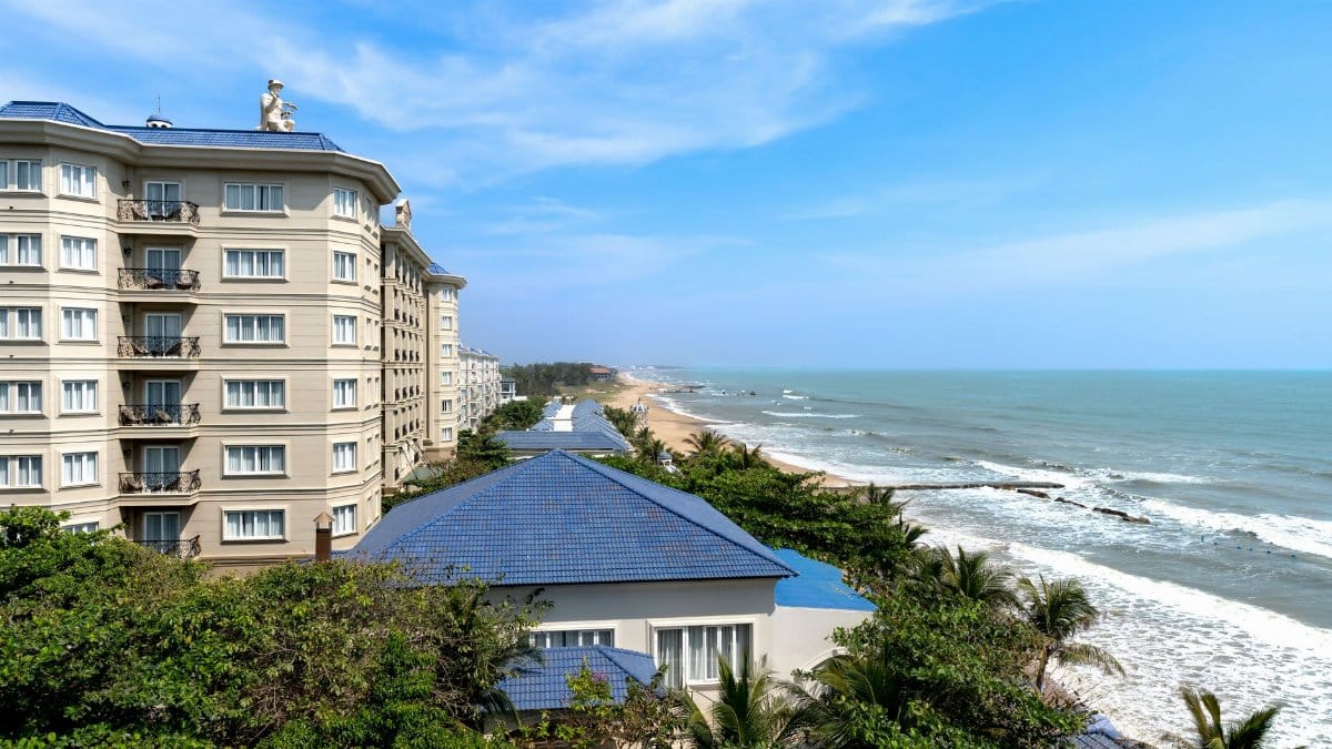 A luxurious beachfront resort overlooking the ocean with clear blue skies and sandy beaches.