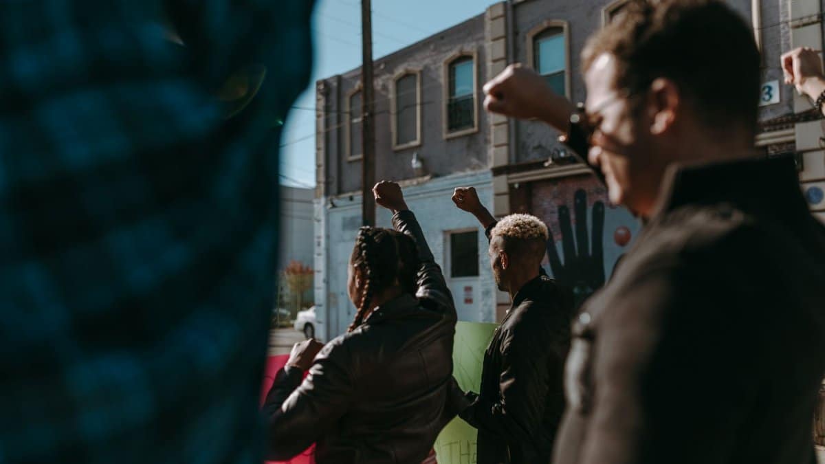 Protesters raising fists during a demonstration in an urban street setting, showing unity and diversity.