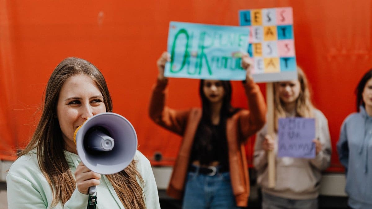 Group of women protesting with signs and a megaphone outdoors.