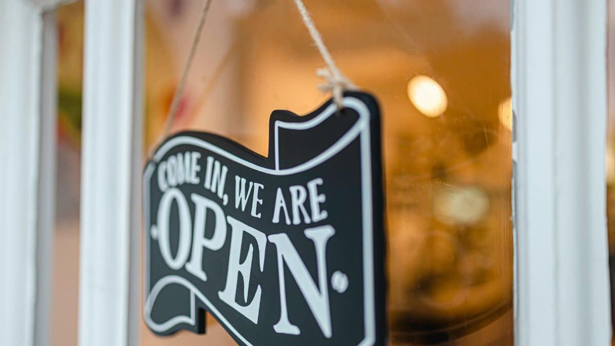 A welcoming open sign hanging on a glass door, inviting customers to enter.