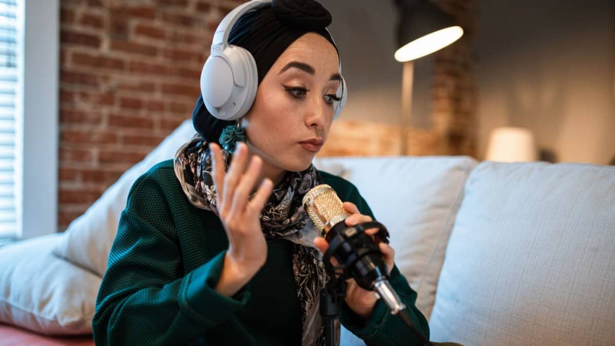 Young woman podcasting with headphones and a microphone indoors.