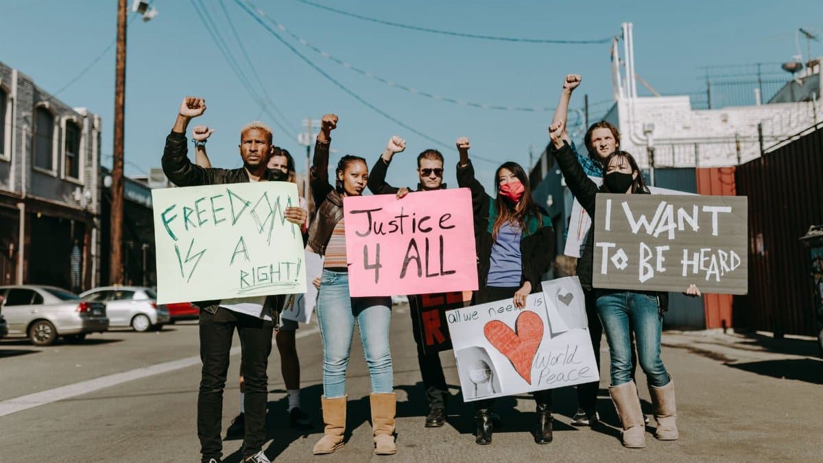 A diverse group of protesters holding signs advocating for justice, freedom, and world peace.