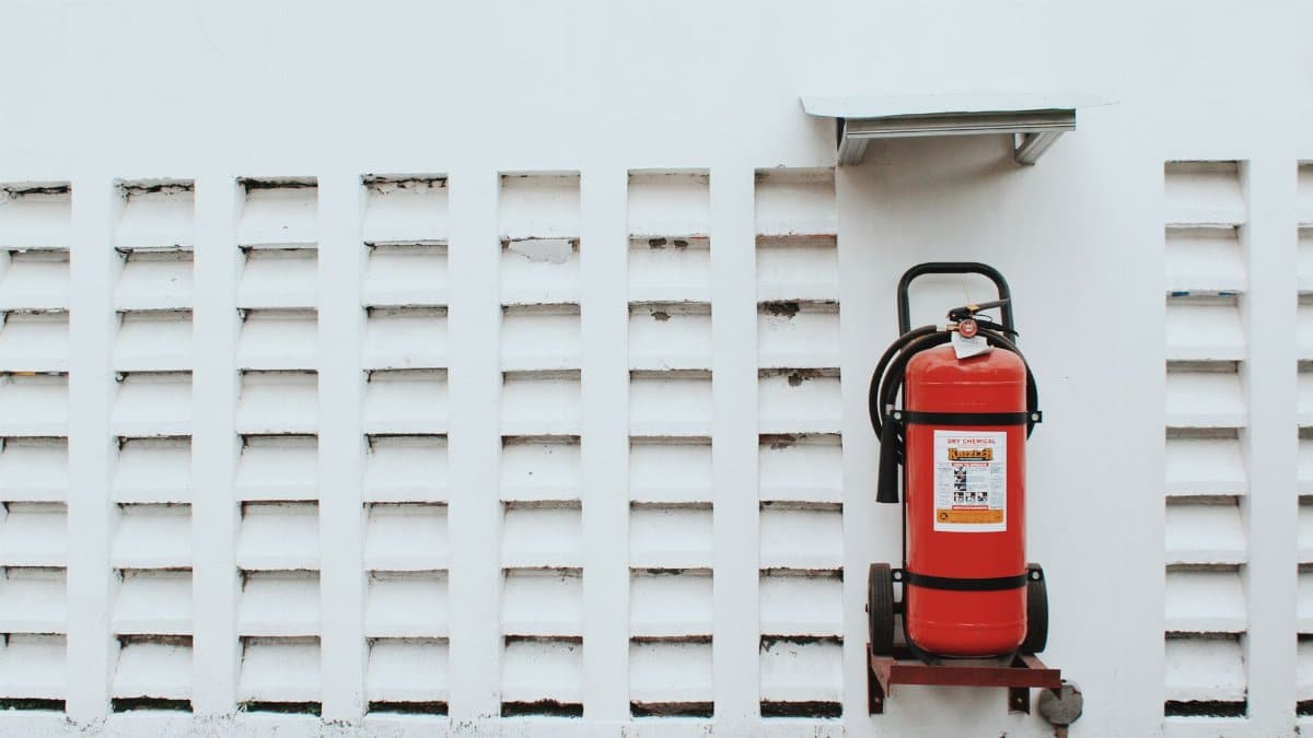 Minimalist image of a red fire extinguisher mounted on a white wall, emphasizing safety.
