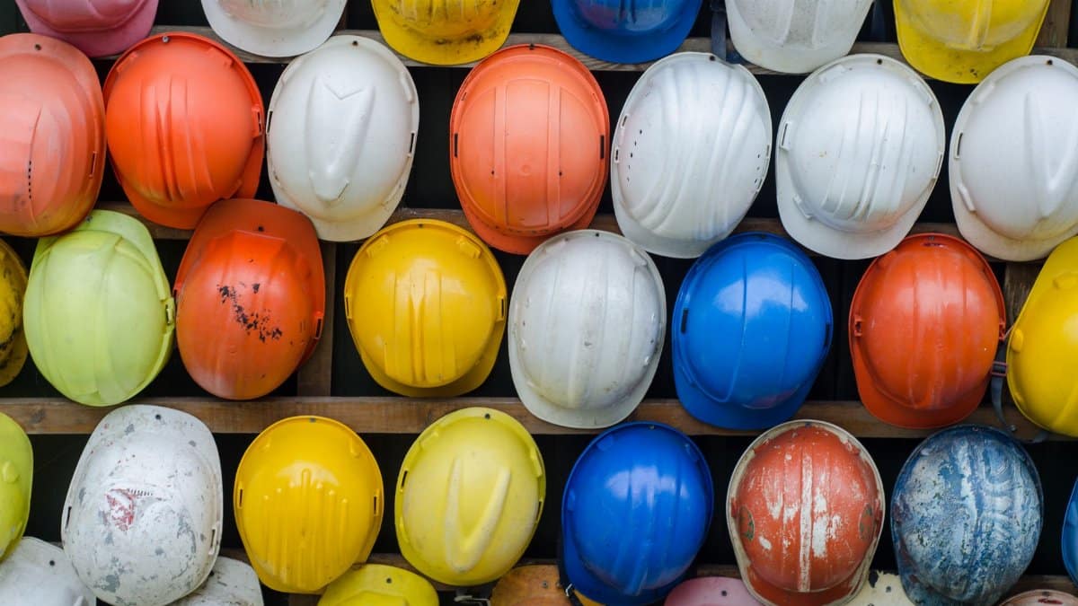 Vibrant collection of industrial safety helmets neatly arranged on a wall.