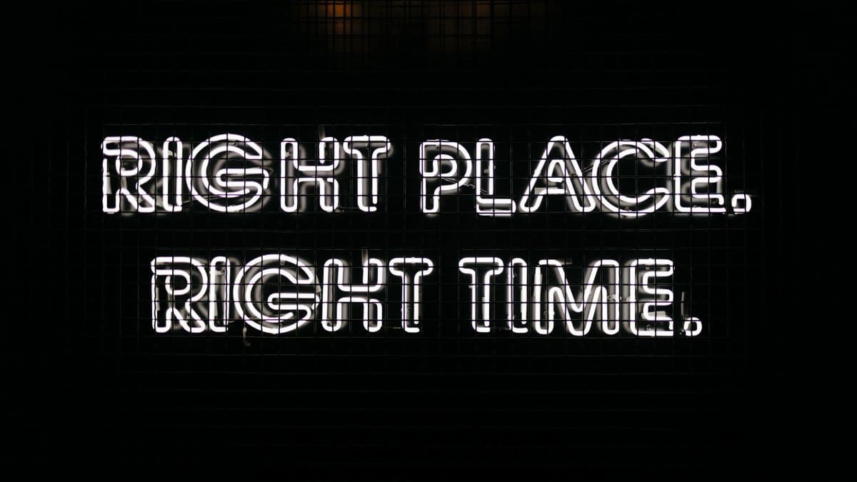 Bright neon sign displaying the text 'Right Place Right Time' against a dark background.