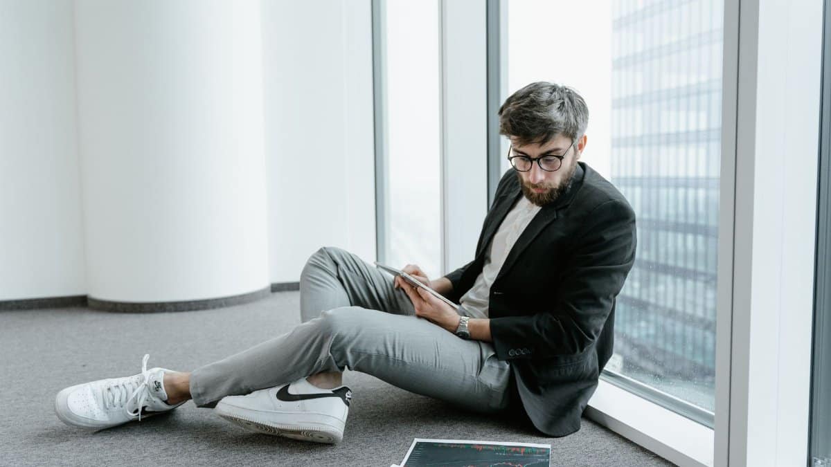 A man in an office setting using a tablet to analyze stock market data with graphs.