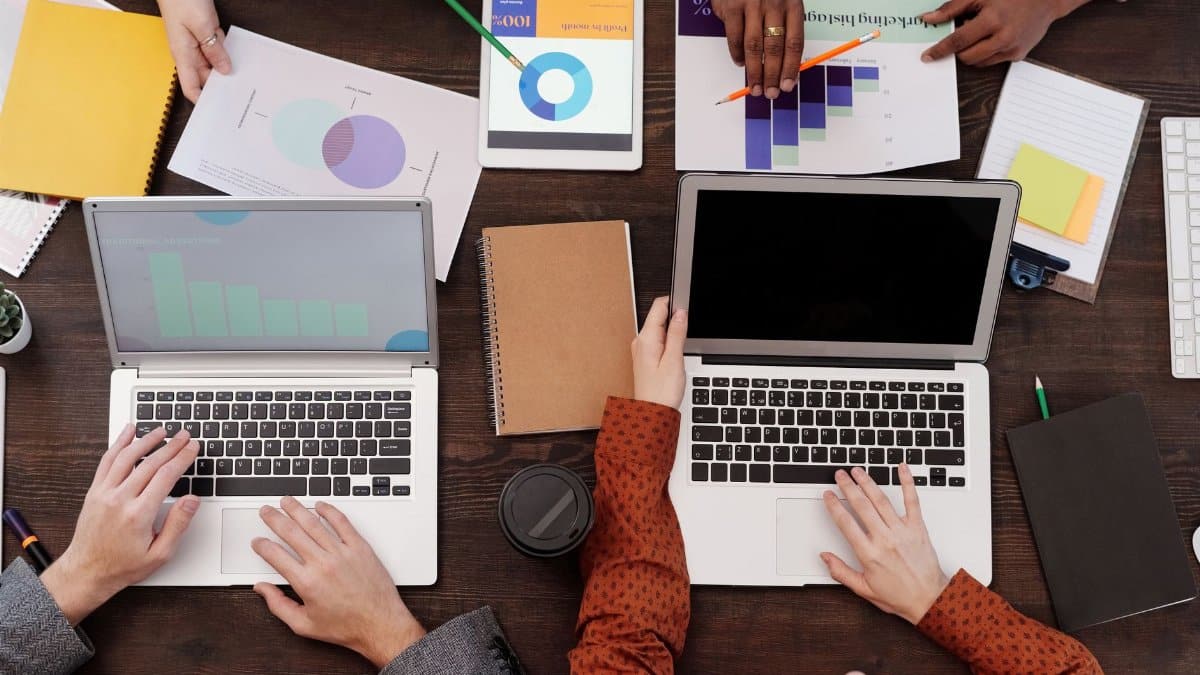 Overhead view of a team discussing digital marketing strategies with laptops and charts.