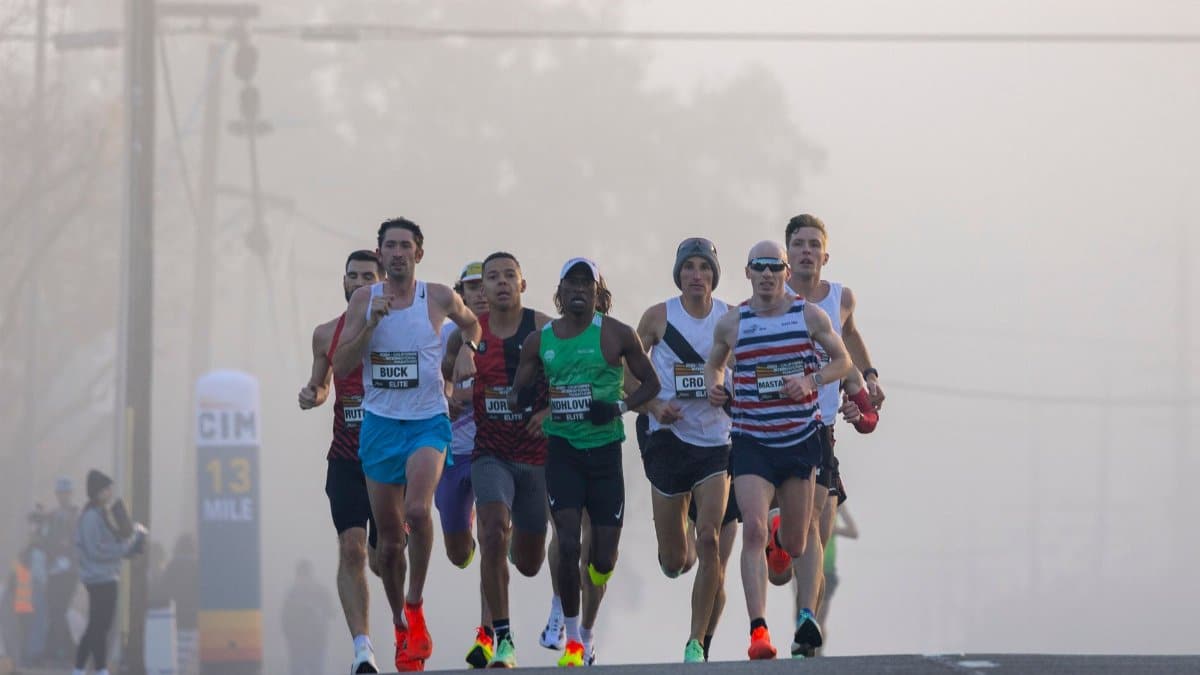 Runners participating in a competitive marathon on a foggy day, showcasing strength and endurance.