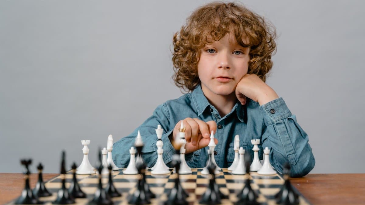A thoughtful child playing chess, focusing on strategic moves with a serious expression.