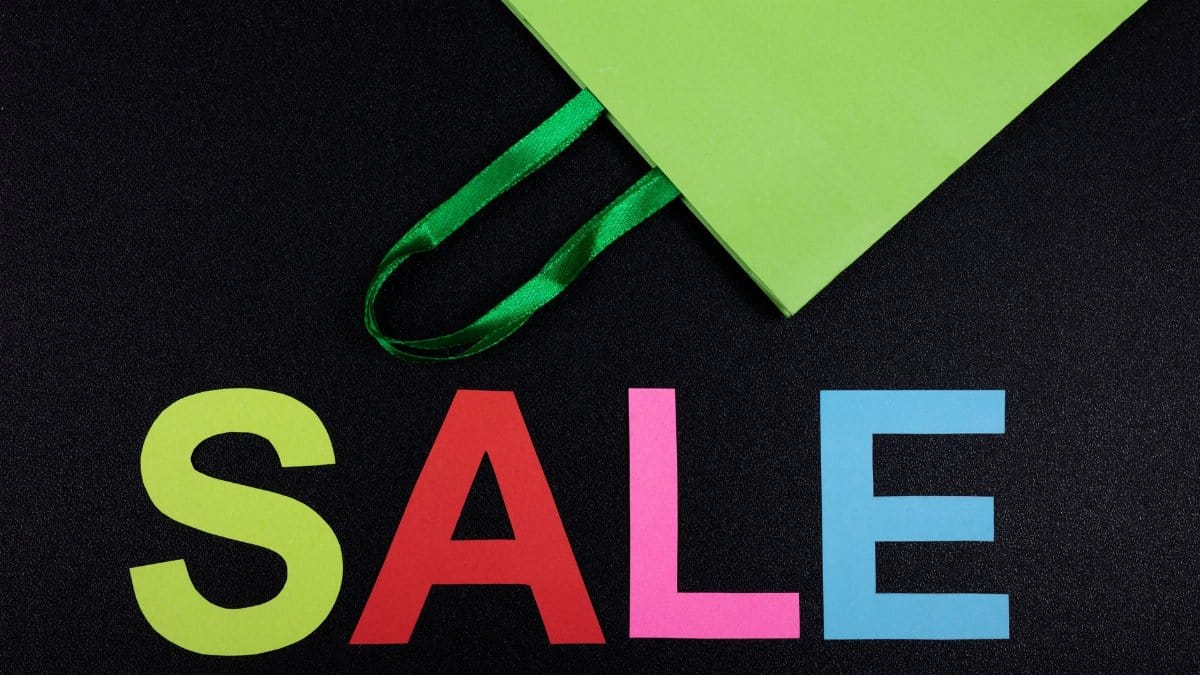 Bright sale text with green shopping bag on black background, perfect for promotions.
