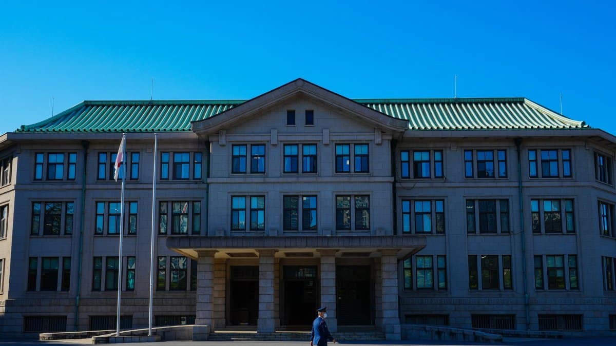 An architectural view of a government building with a person walking past under a clear blue sky.