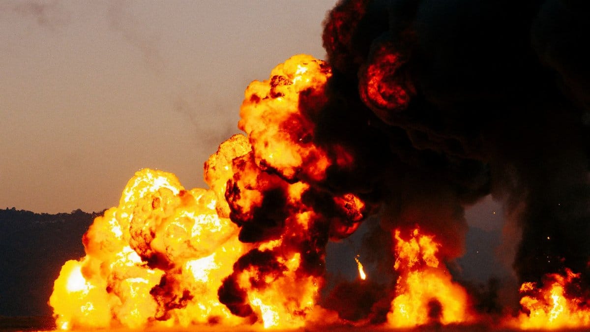 Intense fiery explosion with billowing smoke during twilight outdoors.