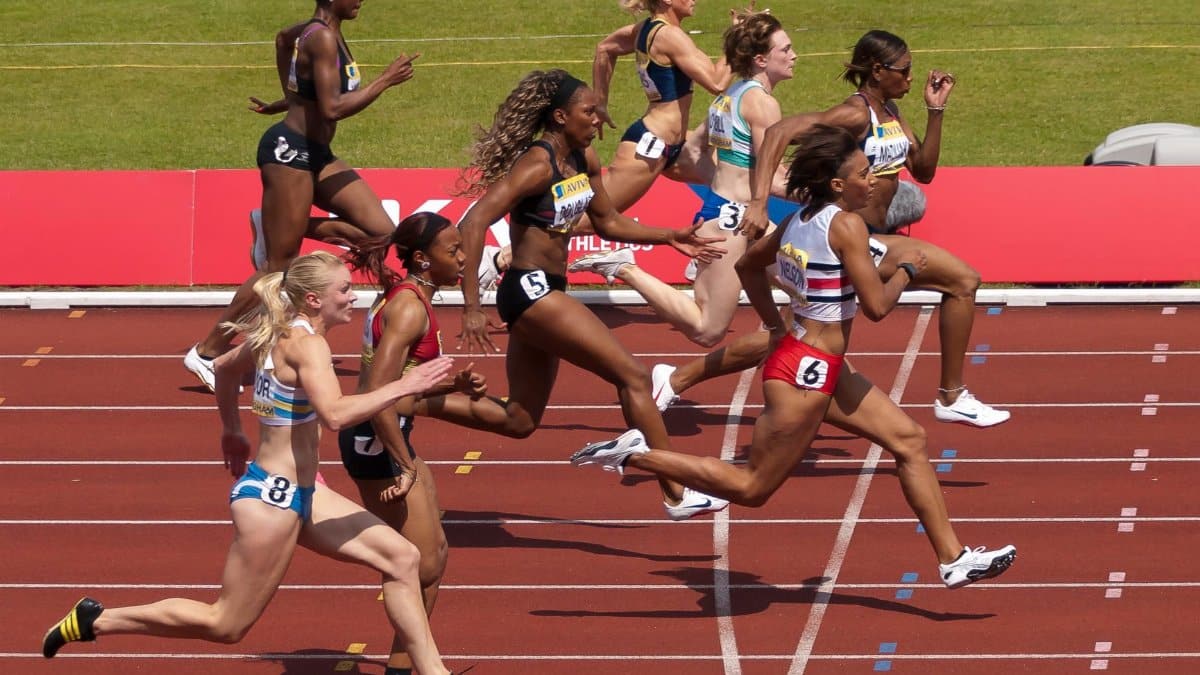 Empowering image of diverse female athletes sprinting in an outdoor track race.