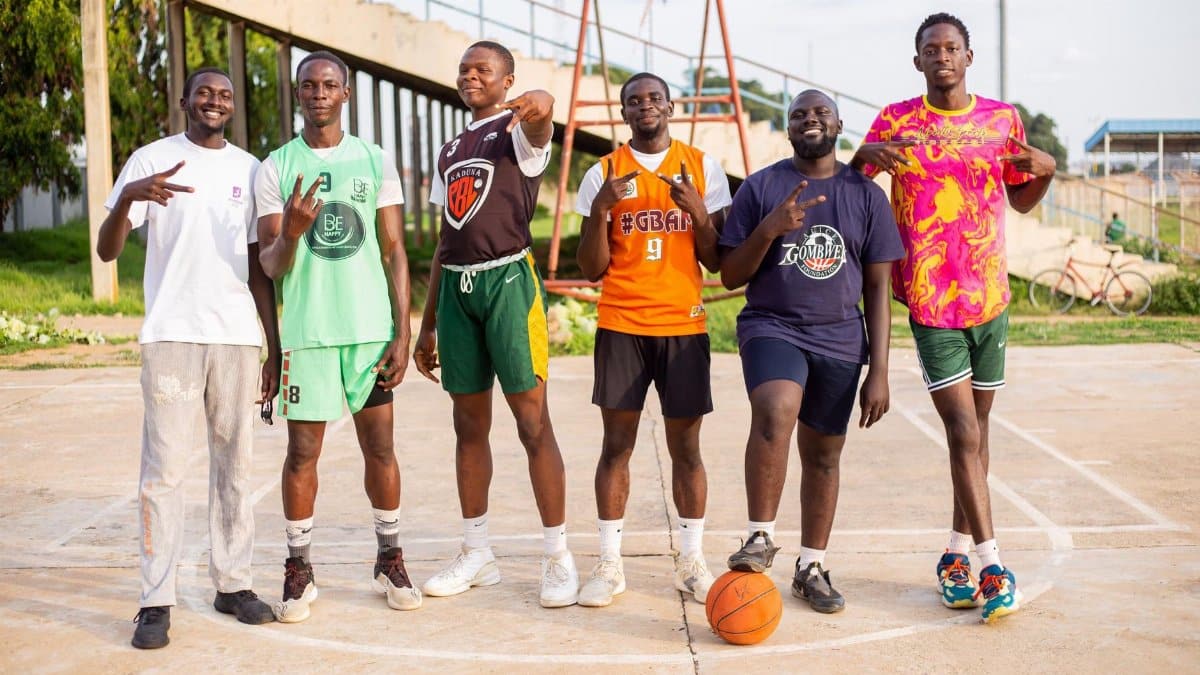 Group of young men posing on an outdoor basketball court, showing camaraderie.