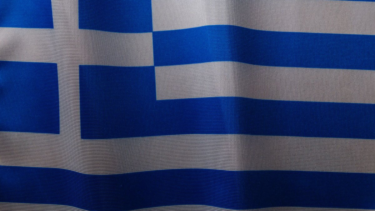 Close-up of the Greek flag waving, highlighting its blue and white stripes representing national unity and culture.