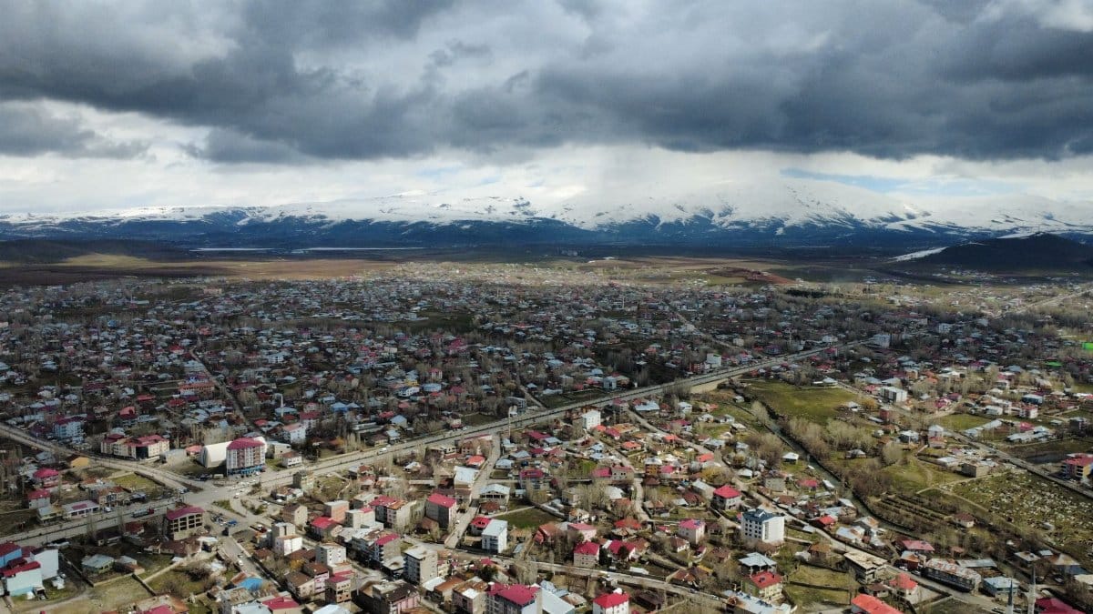 Aerial view of a cityscape with mountainous backdrop and dark clouds.
