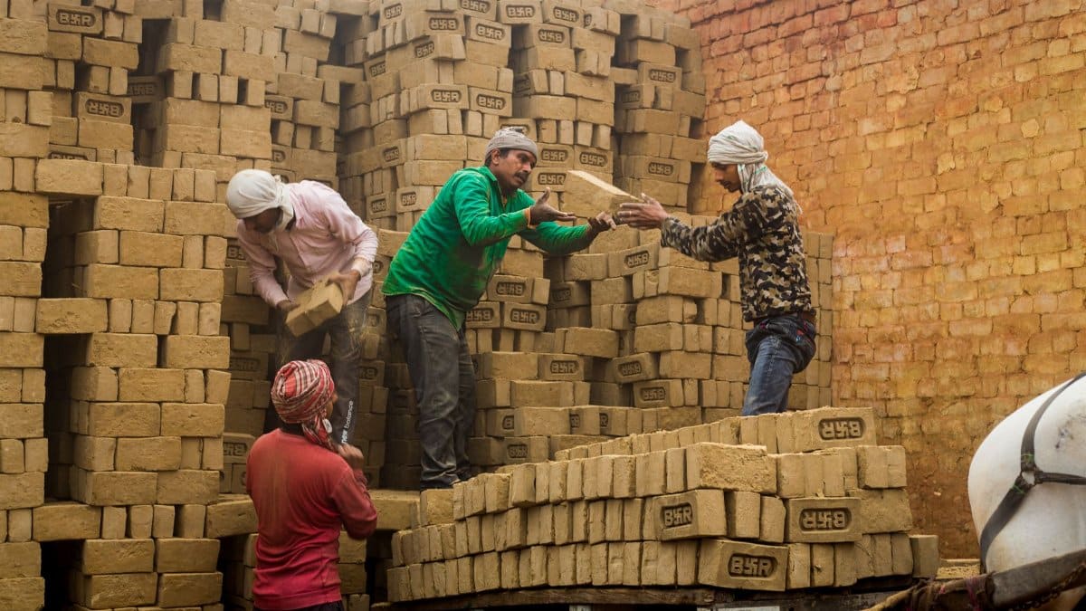 Workers handling bricks in an Indian kiln, depicting traditional craftsmanship and labor.