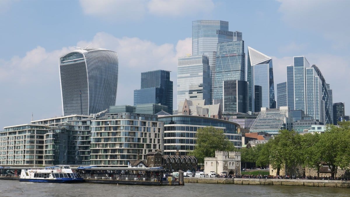 Modern skyscrapers in London's financial district along the River Thames under a bright sky.