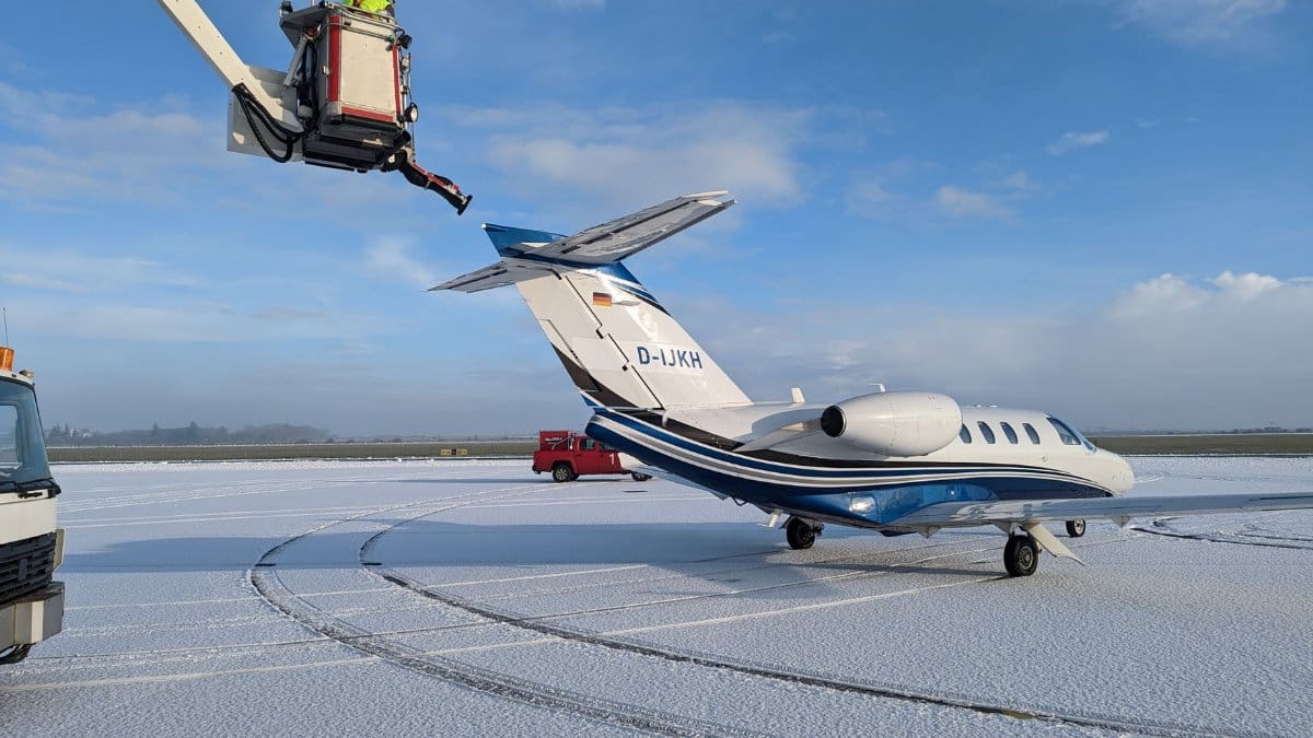 A private jet undergoing de-icing on a snow-covered airport tarmac in winter weather.