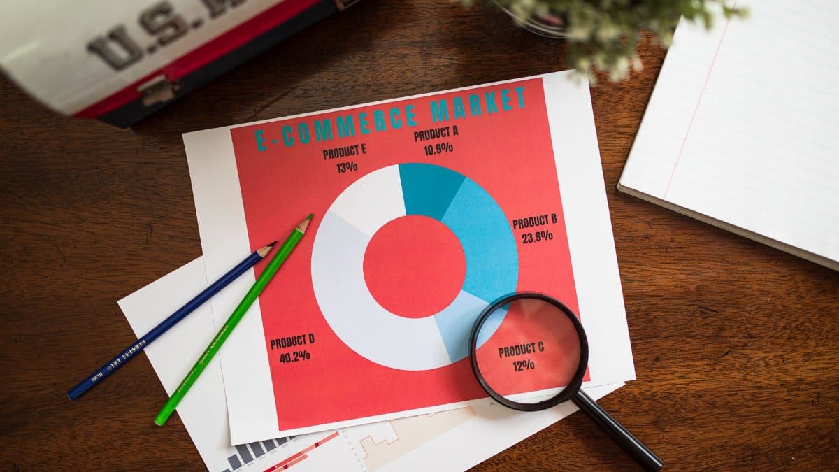 Top view of e-commerce data charts with a magnifying glass on a wooden table.