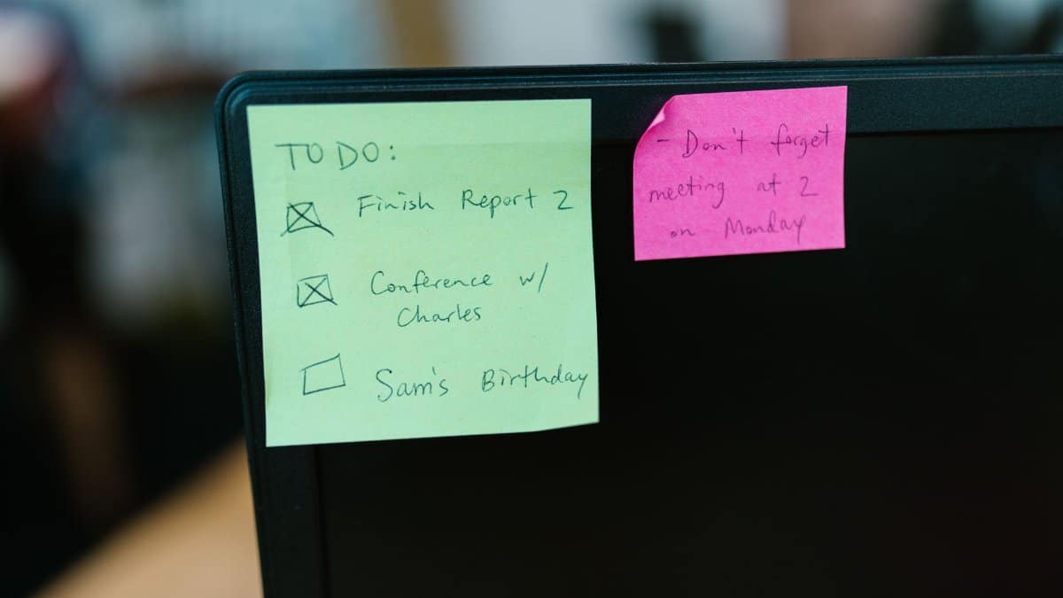 Colorful sticky notes with reminders and to-do list on an office monitor.