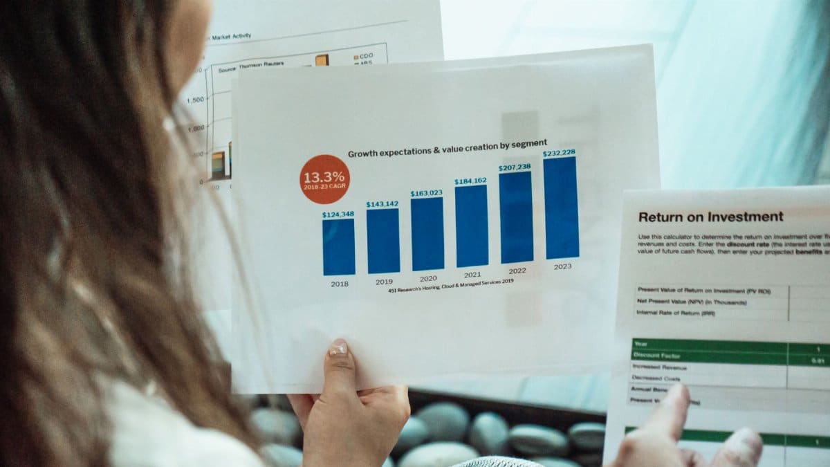 Person analyzing financial graphs and ROI reports, focusing on investment growth.