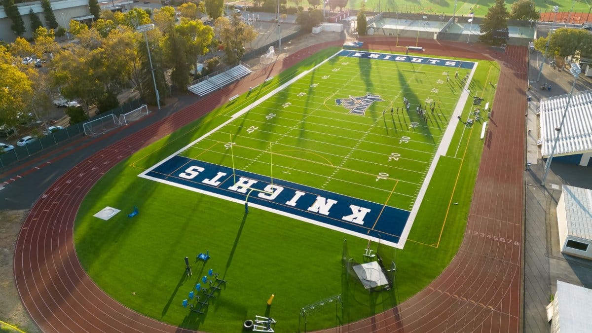 Stunning aerial shot of a high school football field and track at sunset. Perfect layout for sports events.