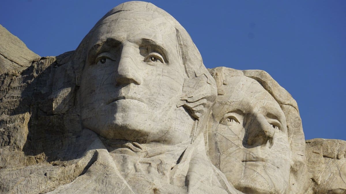 A detailed close-up shot of Mount Rushmore's iconic presidential sculptures against a clear blue sky.