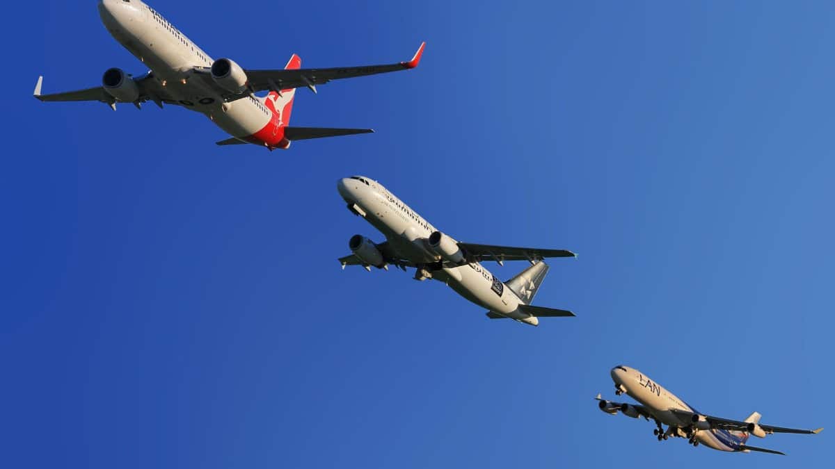 Three commercial airplanes soaring through a clear blue sky, highlighting aviation technology.