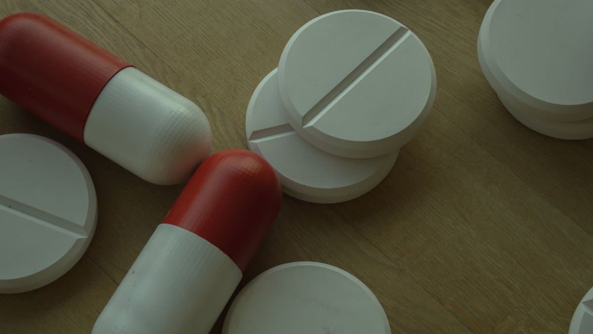 Assorted white tablets and red capsules on a wooden surface, emphasizing medications.