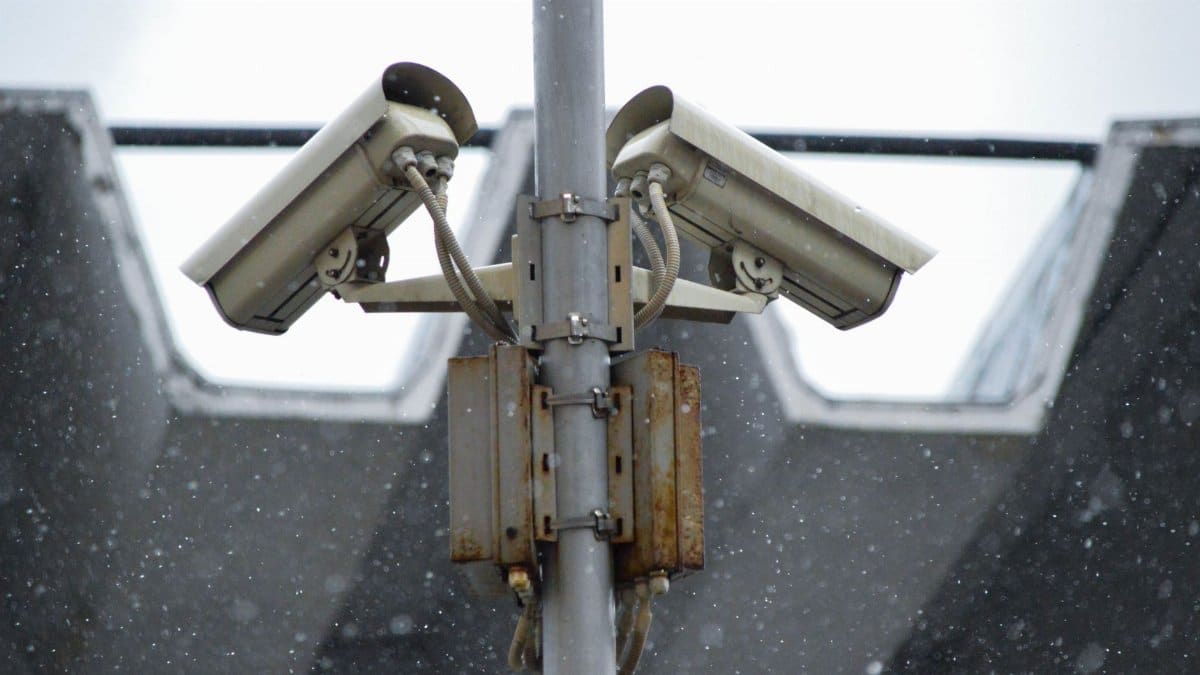 Close-up view of surveillance cameras during a snowfall in urban Москва setting.