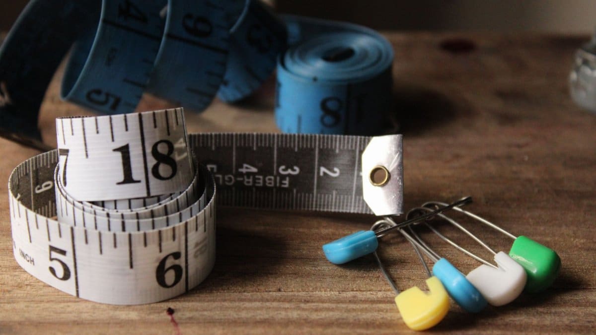 Tape measures and colorful sewing pins on a wooden surface.
