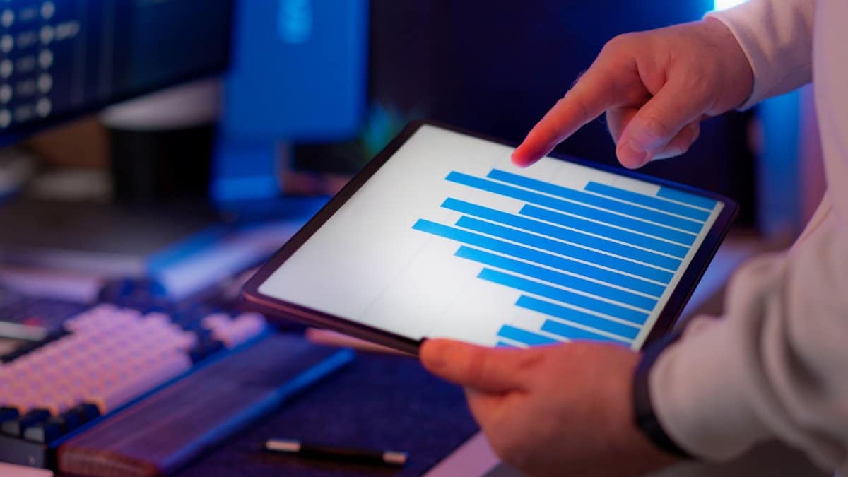 Business professional analyzing bar chart on tablet in office setting, highlighting data insights.