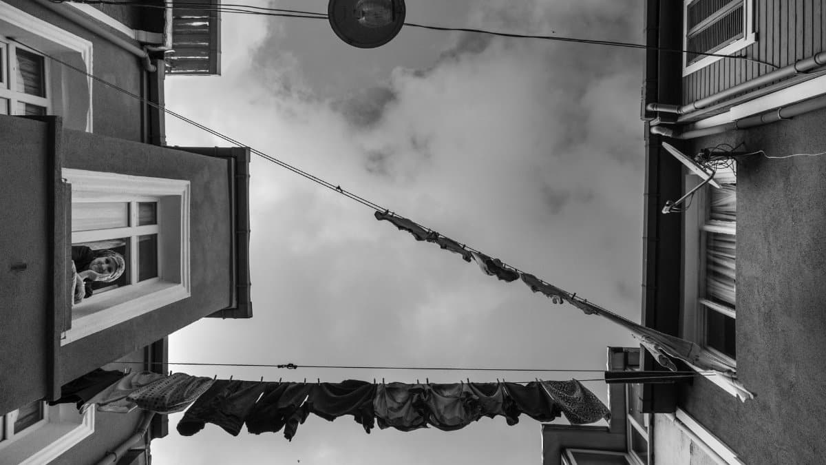 Black and white view of clothesline between buildings, capturing urban life.