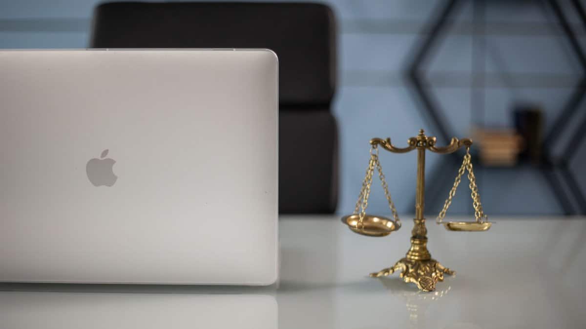 Elegant balance of technology and justice scales on an office desk.