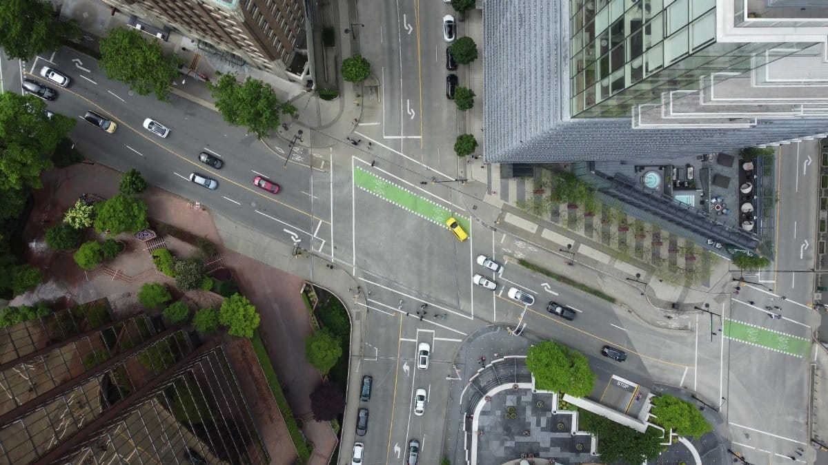 Aerial shot of a busy city intersection with cars and skyscrapers.