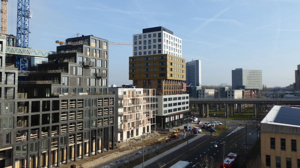 A lively urban scene with modern buildings under construction and city traffic.