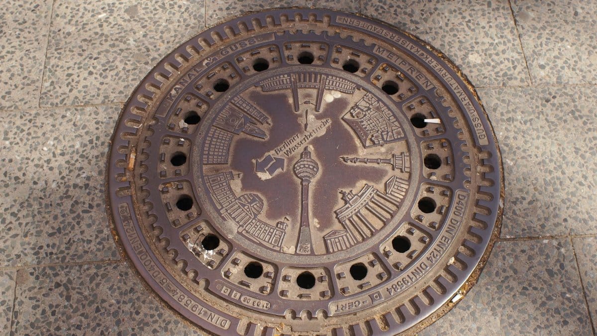Intricate manhole cover in Berlin featuring iconic city landmarks in a detailed design.