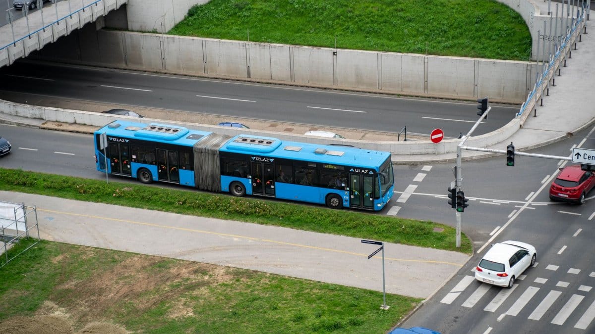 A blue bus navigating city streets from an aerial perspective, showcasing urban transportation.
