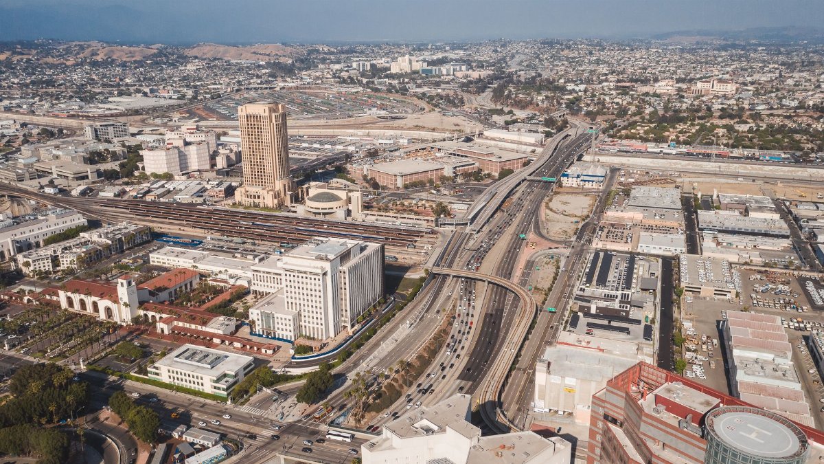 Aerial shot of Los Angeles cityscape with highways and urban buildings.
