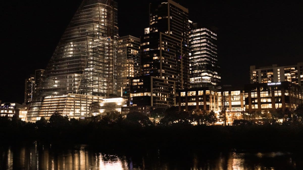 Illuminated skyscrapers reflecting in the river at night in downtown Austin, Texas.