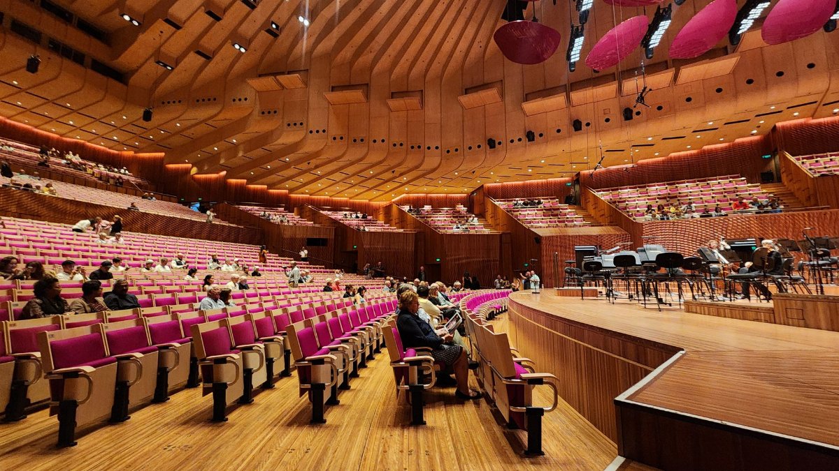Spacious interior view of Sydney Opera House concert hall with seating and stage.